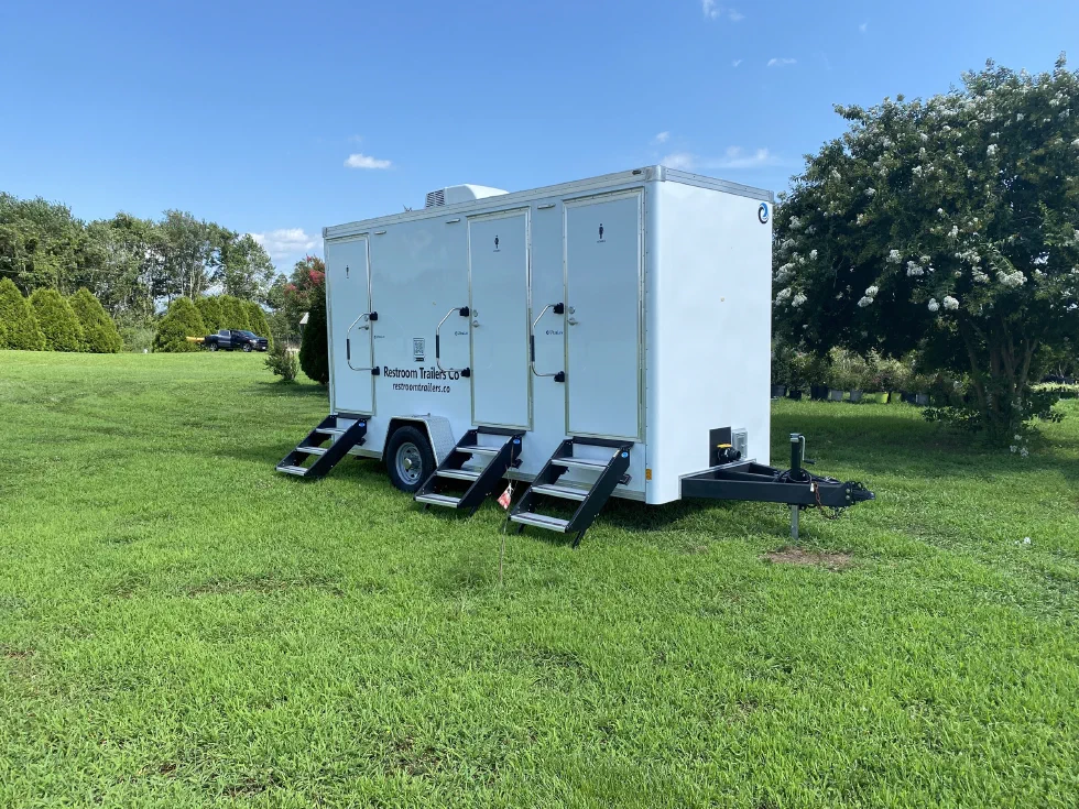 Restroom trailer on site with the tow hitch and stabilizing jack visible at the front