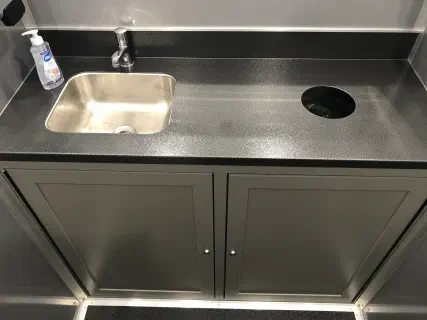 Stainless sink set into a vanity counter with soap dispenser and running water