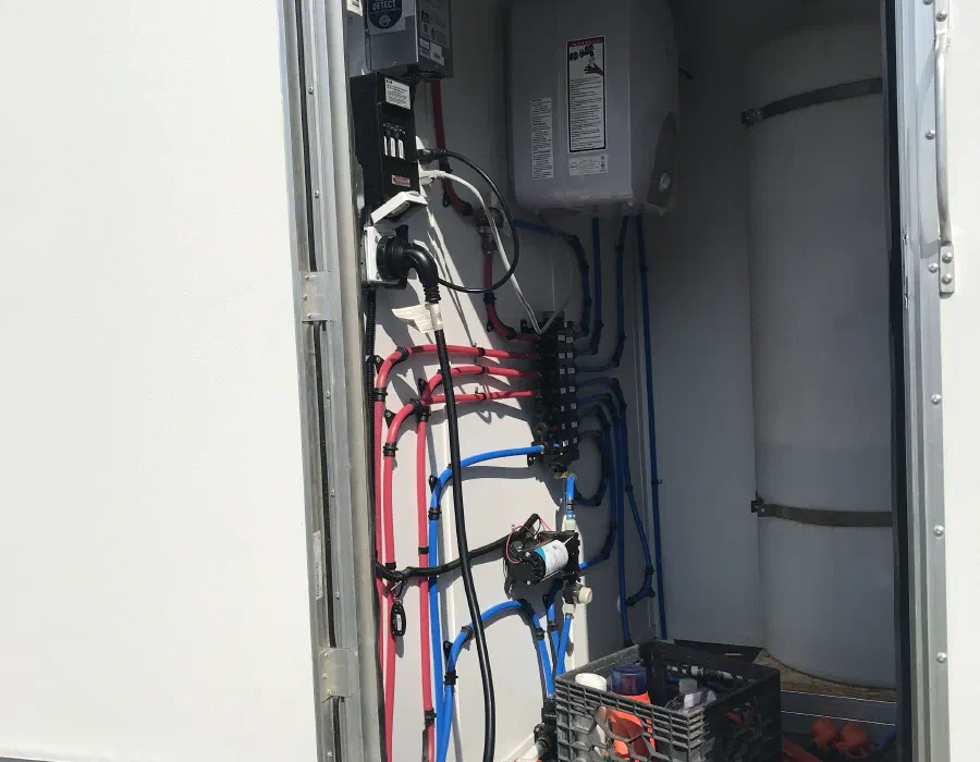 Open utility compartment with the fresh water tank, pump, water heater and electrical panel